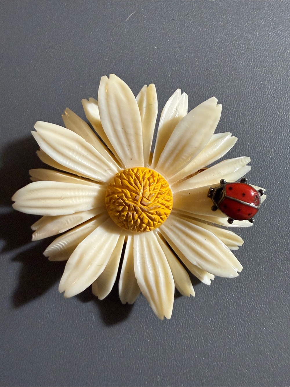 vintage 1930s brooch featuring a carved faux ivory daisy and a small ladybug
